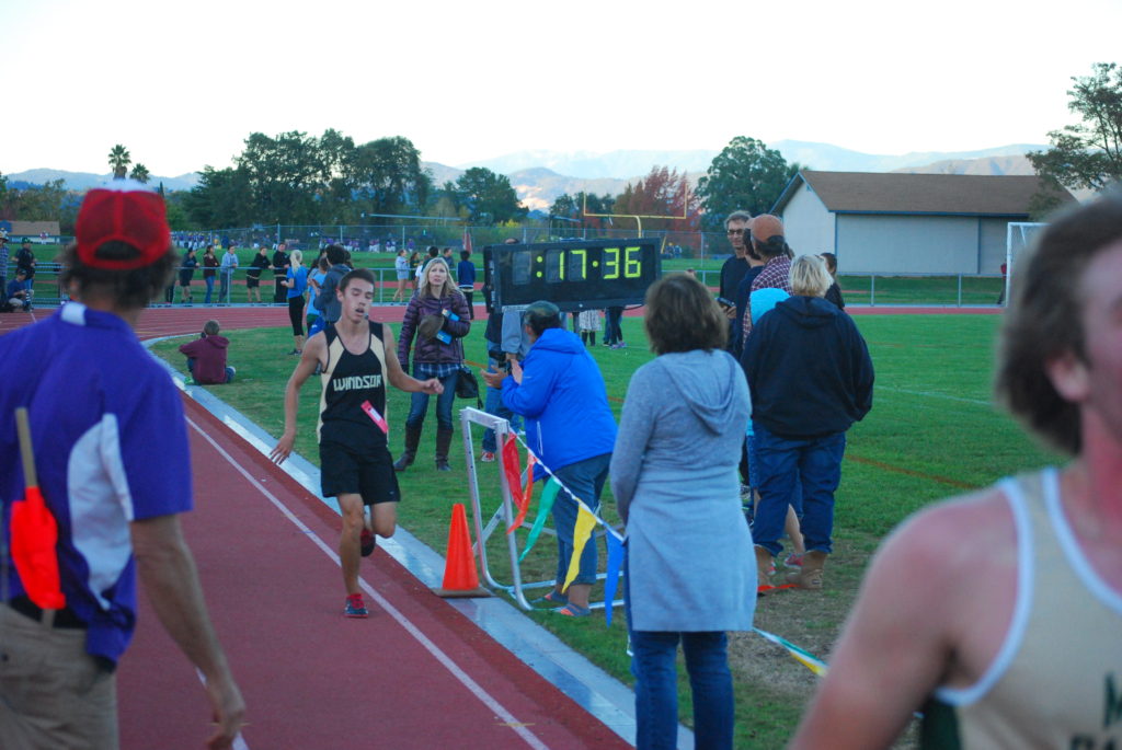 Athlete prepares for pole vault on a track with others watching.