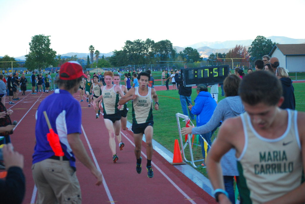 Athlete prepares for pole vault on a track with others watching.