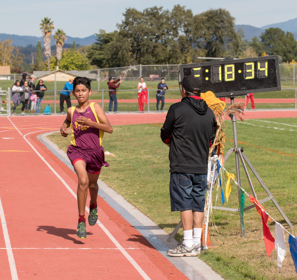 Athlete prepares for pole vault on a track with others watching.