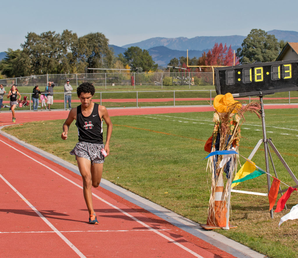 Athlete prepares for pole vault on a track with others watching.