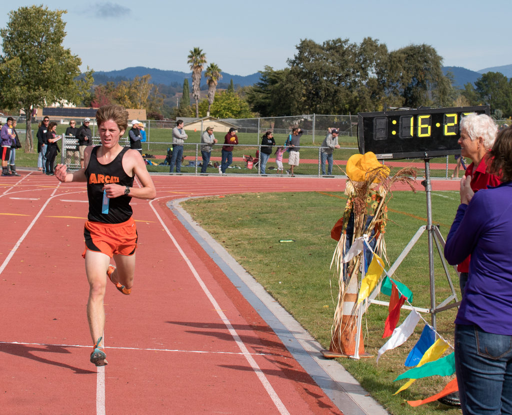 Athlete prepares for pole vault on a track with others watching.