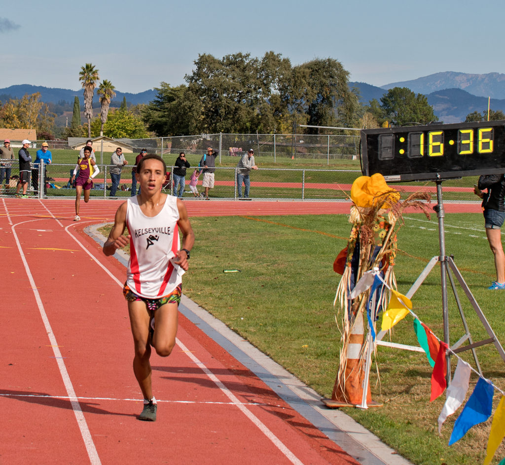 Athlete prepares for pole vault on a track with others watching.