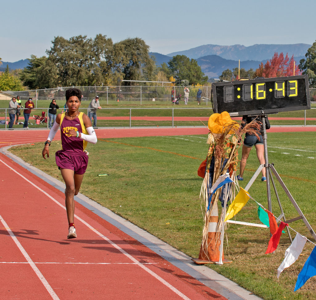 Athlete prepares for pole vault on a track with others watching.