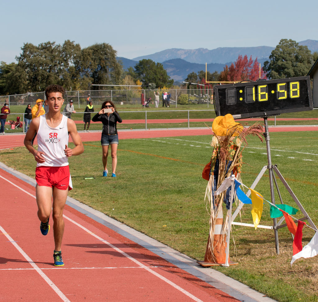 Athlete prepares for pole vault on a track with others watching.