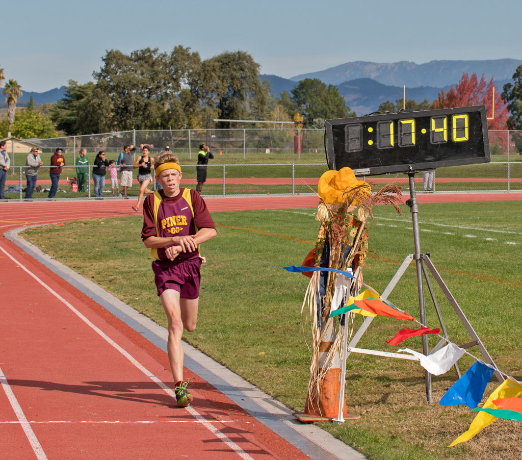 Athlete prepares for pole vault on a track with others watching.