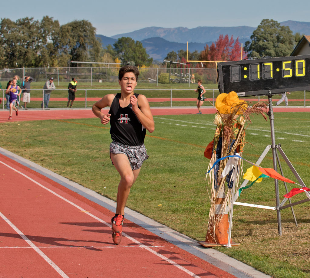 Athlete prepares for pole vault on a track with others watching.