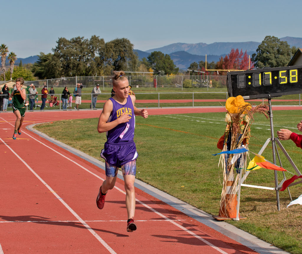 Athlete prepares for pole vault on a track with others watching.