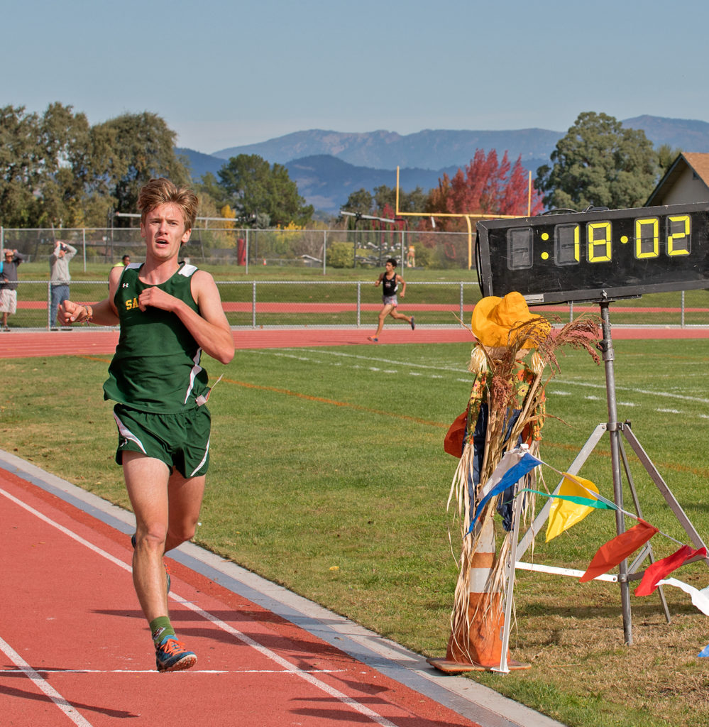 Athlete prepares for pole vault on a track with others watching.