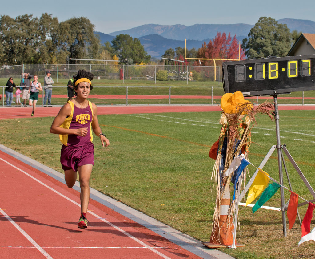Athlete prepares for pole vault on a track with others watching.
