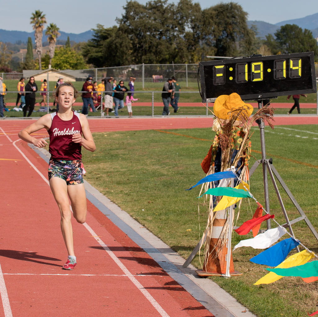 Athlete prepares for pole vault on a track with others watching.
