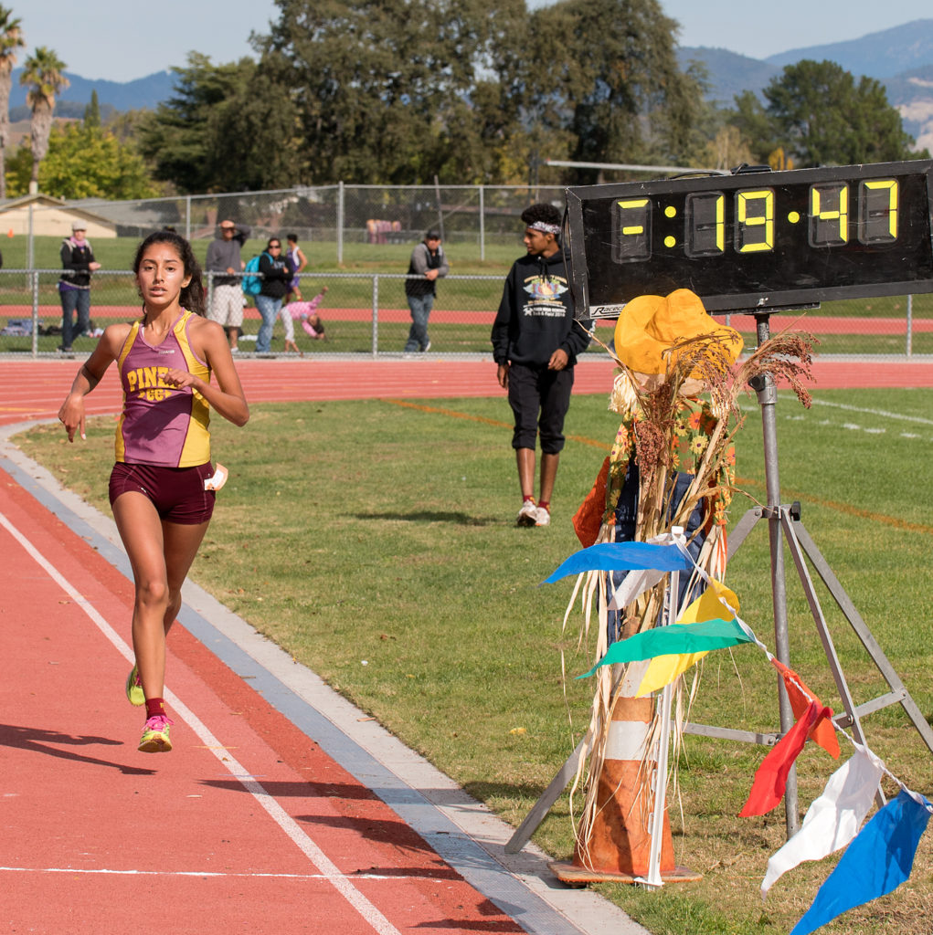 Athlete prepares for pole vault on a track with others watching.