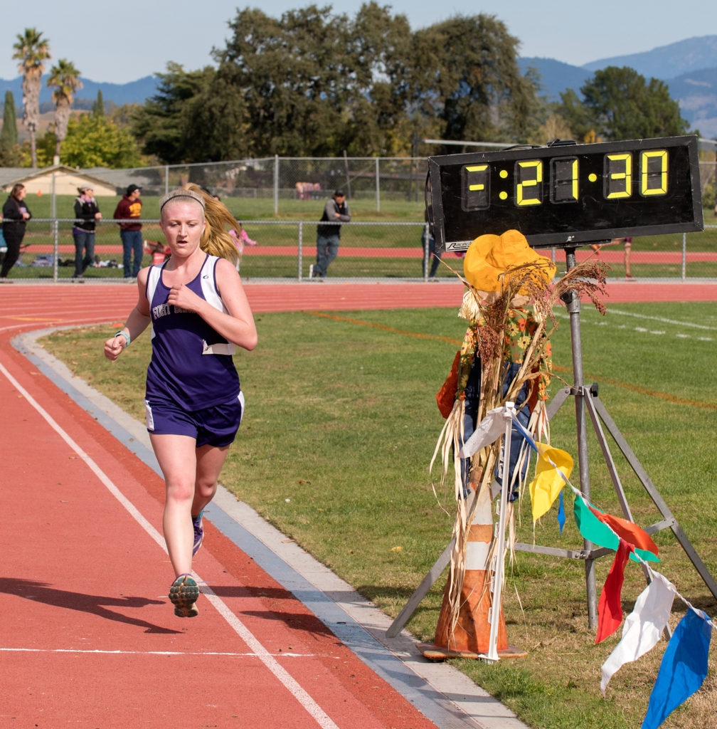 Athlete prepares for pole vault on a track with others watching.