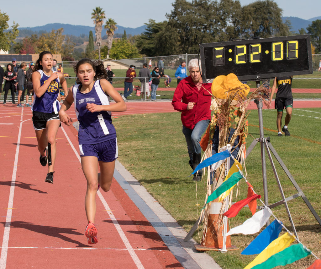 Athlete prepares for pole vault on a track with others watching.