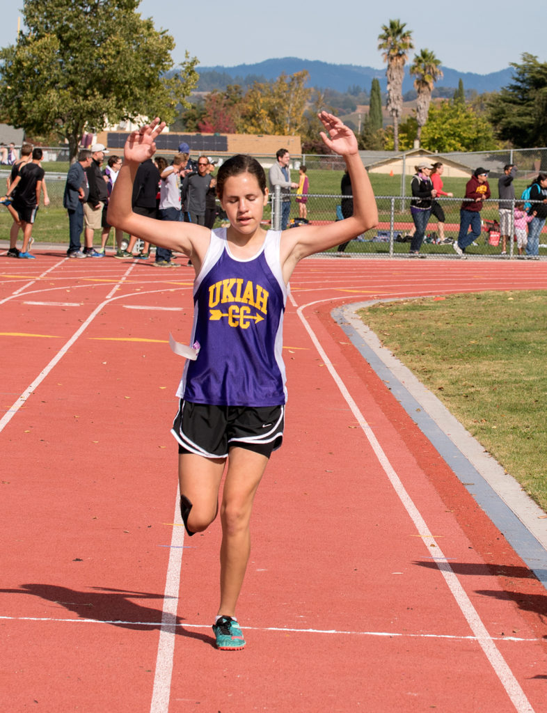 Athlete prepares for pole vault on a track with others watching.