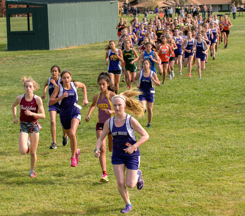 Athlete prepares for pole vault on a track with others watching.
