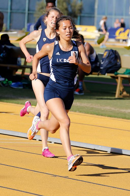 Athlete prepares for pole vault on a track with others watching.