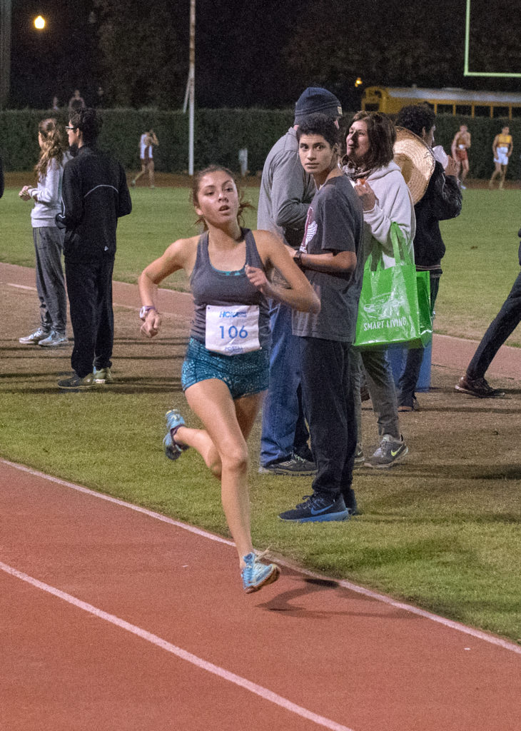 Athlete prepares for pole vault on a track with others watching.