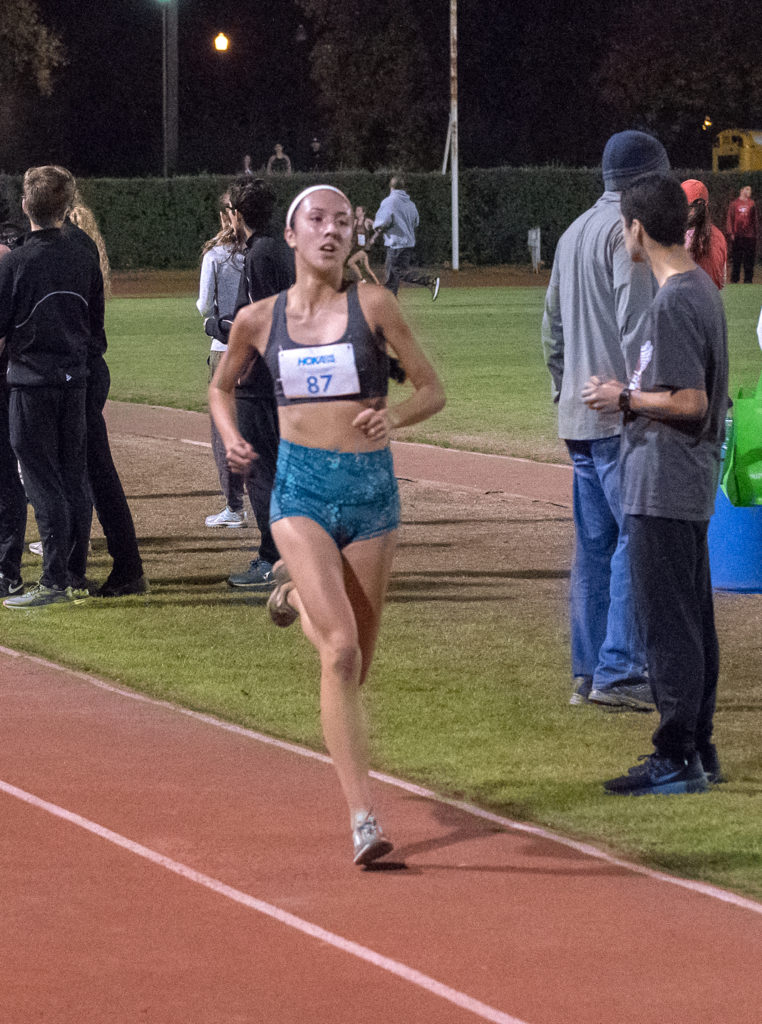Athlete prepares for pole vault on a track with others watching.