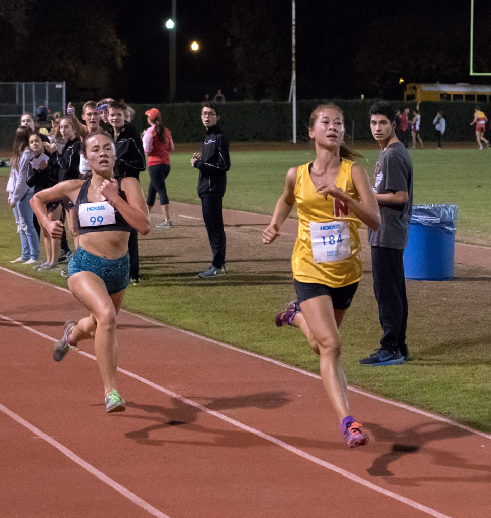 Athlete prepares for pole vault on a track with others watching.