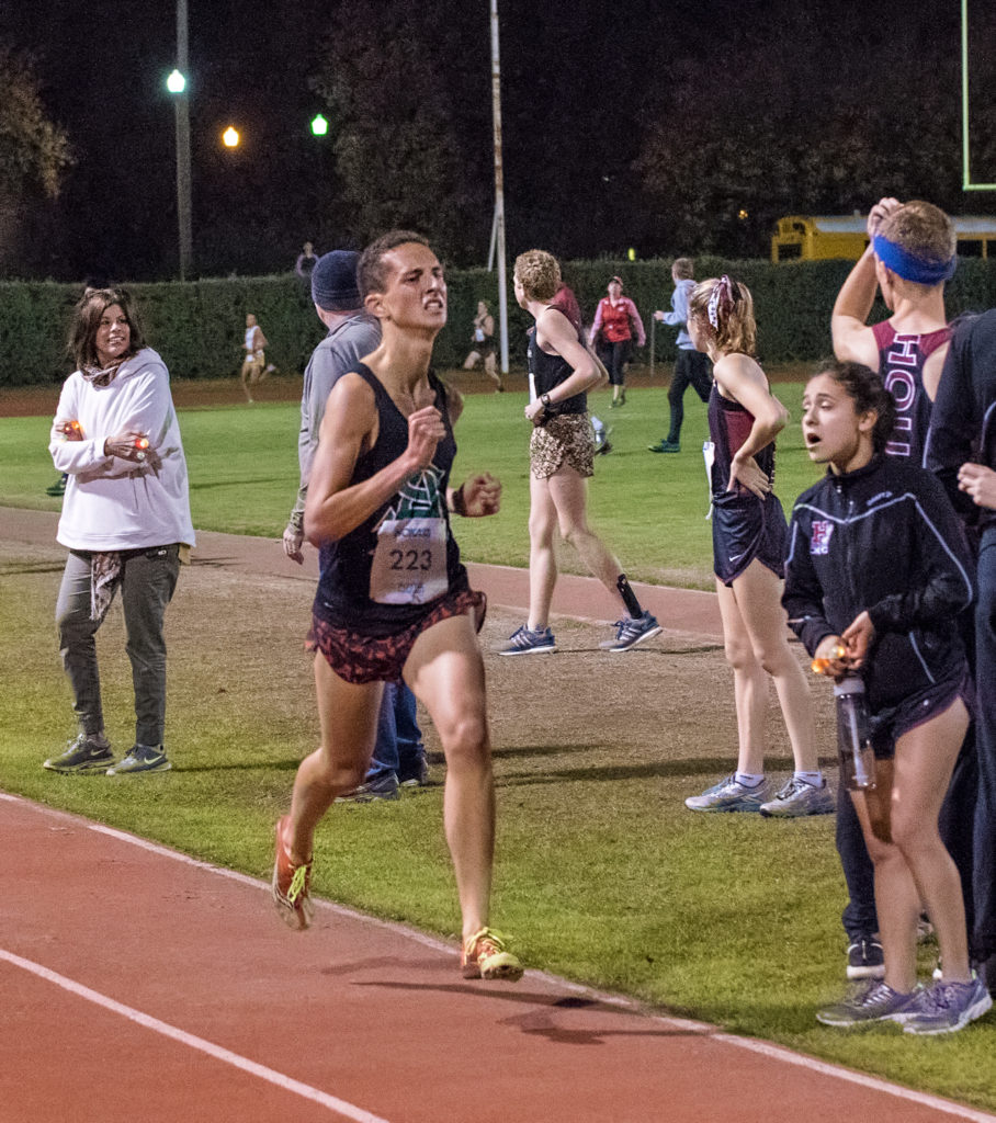 Athlete prepares for pole vault on a track with others watching.