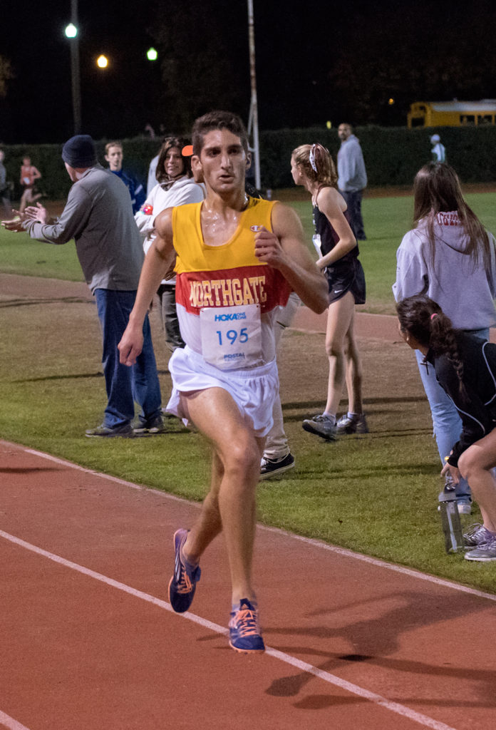 Athlete prepares for pole vault on a track with others watching.