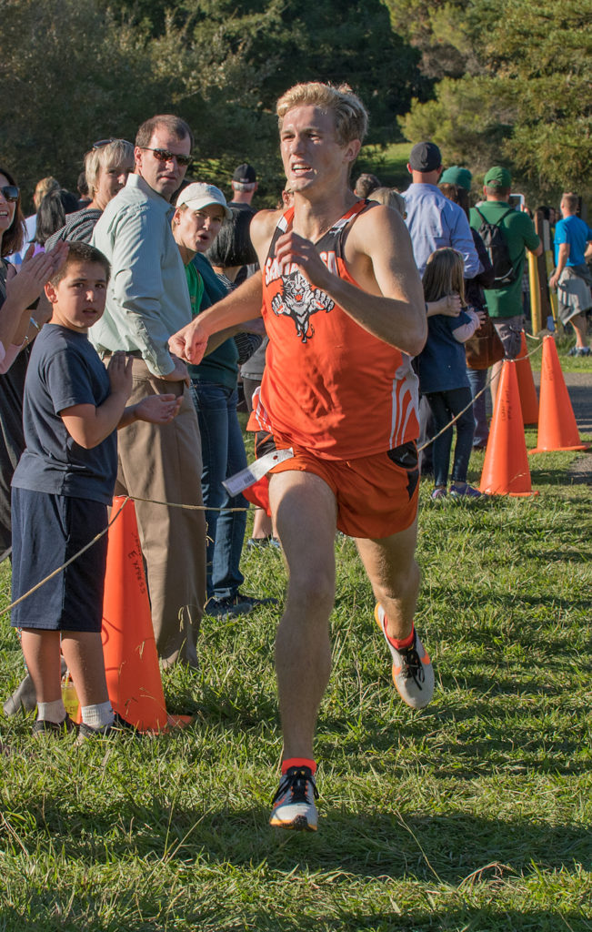 Athlete prepares for pole vault on a track with others watching.