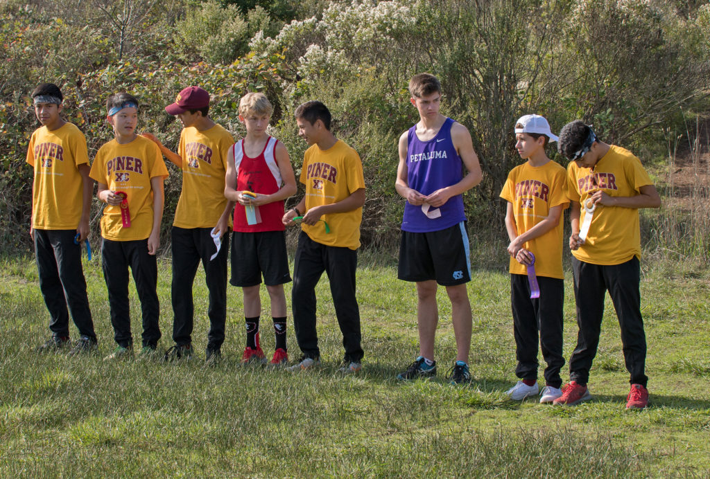 Athlete prepares for pole vault on a track with others watching.