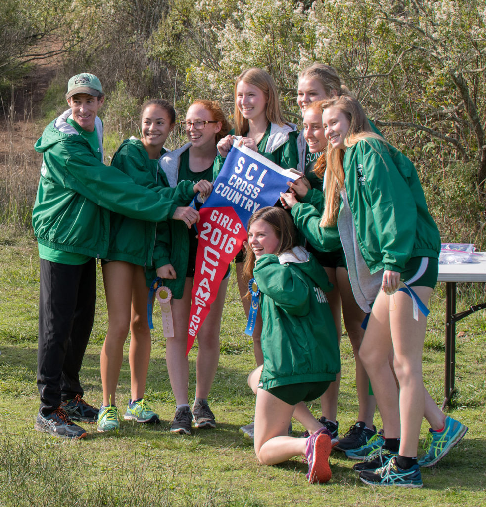 Athlete prepares for pole vault on a track with others watching.