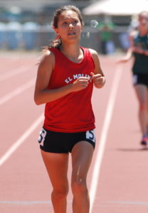 Athlete prepares for pole vault on a track with others watching.