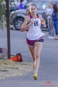 Athlete prepares for pole vault on a track with others watching.