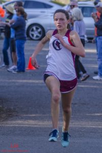 Athlete prepares for pole vault on a track with others watching.