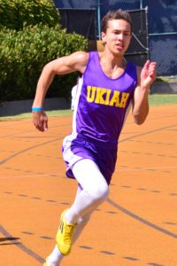 Athlete prepares for pole vault on a track with others watching.