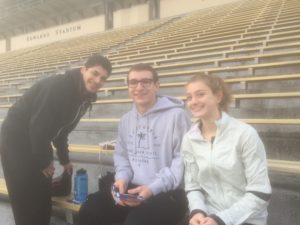 Athlete prepares for pole vault on a track with others watching.