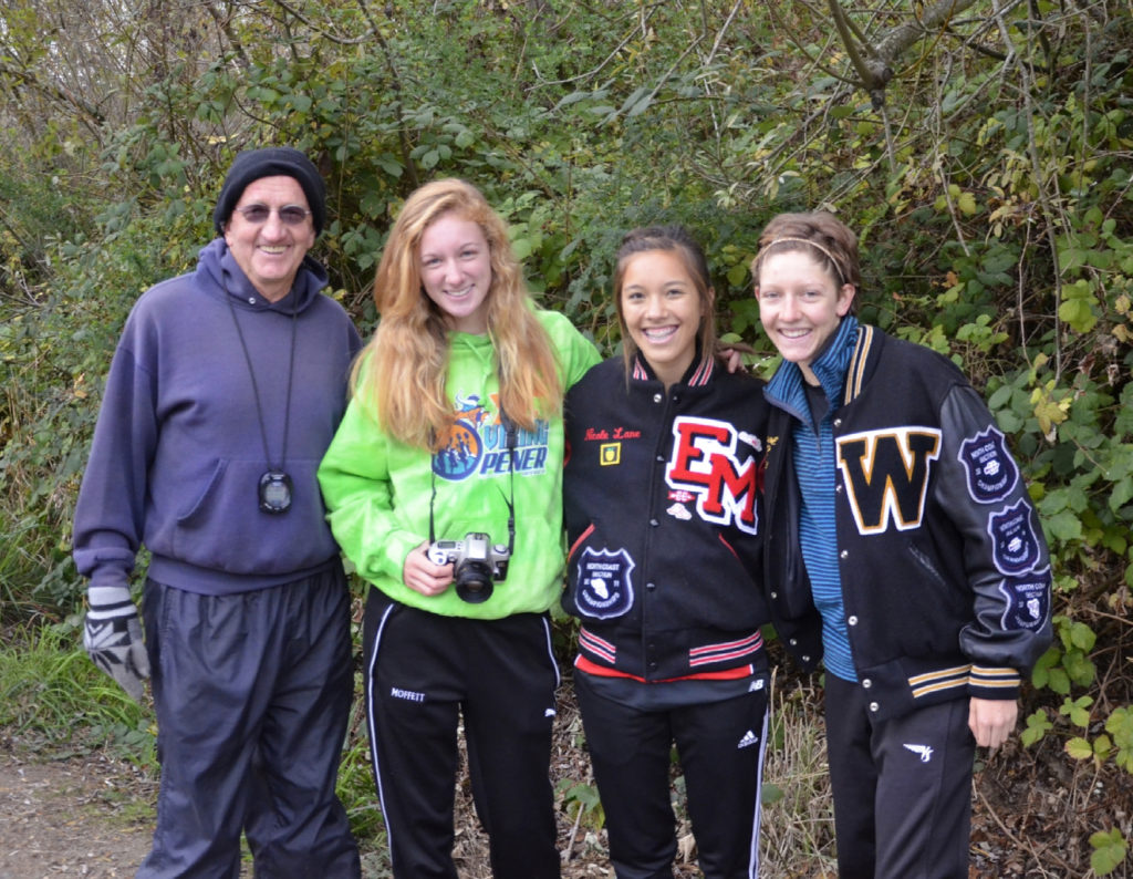 Athlete prepares for pole vault on a track with others watching.