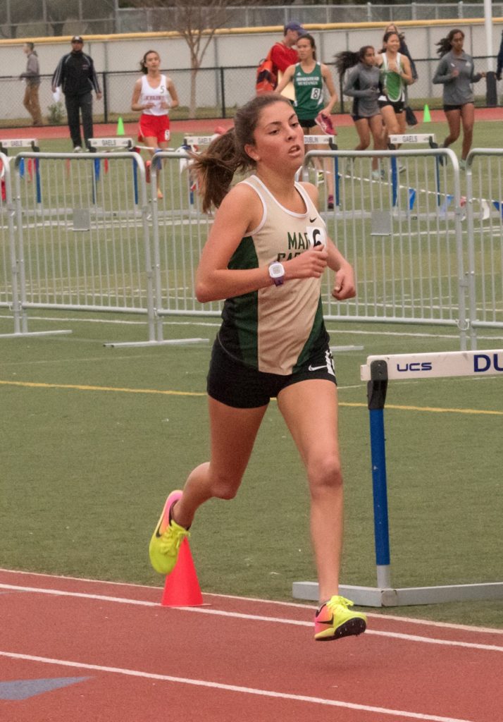 Athlete prepares for pole vault on a track with others watching.