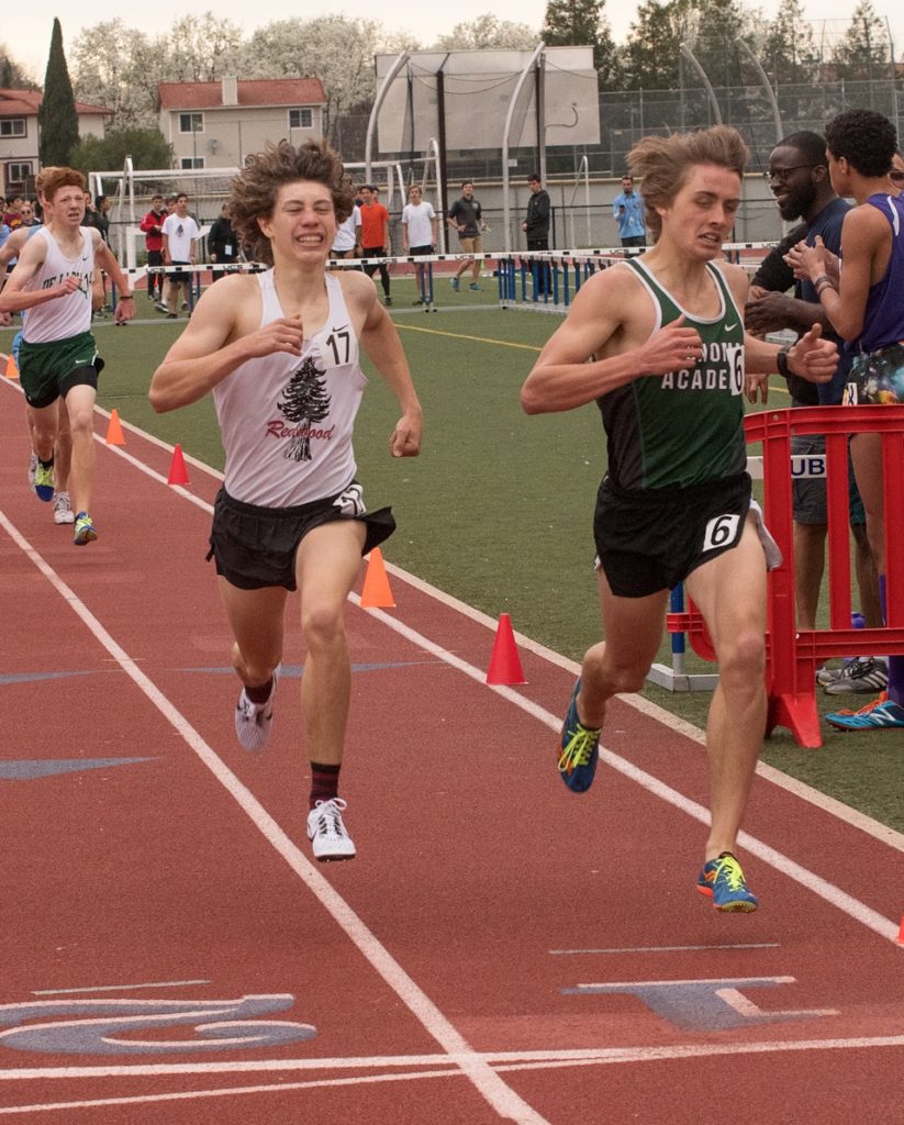 Athlete prepares for pole vault on a track with others watching.