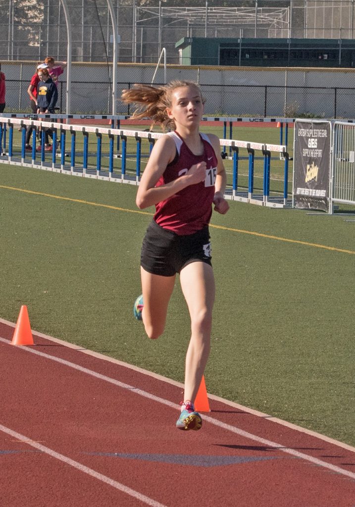Athlete prepares for pole vault on a track with others watching.