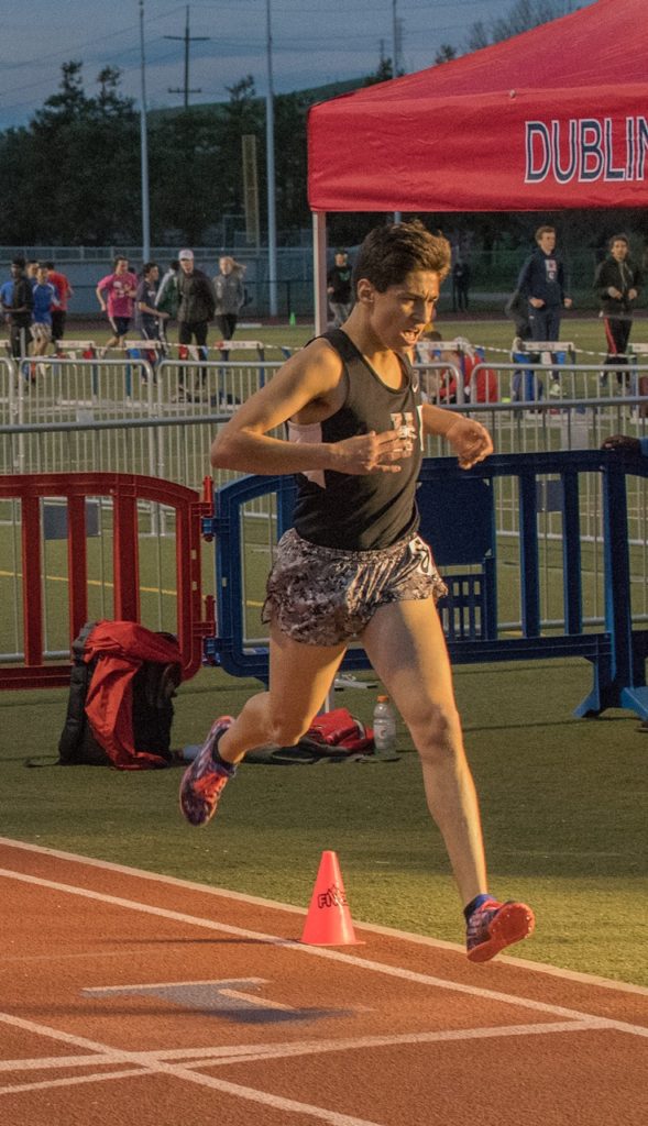 Athlete prepares for pole vault on a track with others watching.