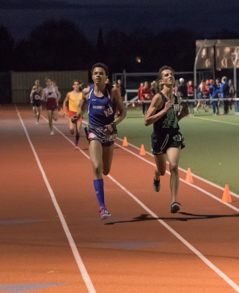 Athlete prepares for pole vault on a track with others watching.