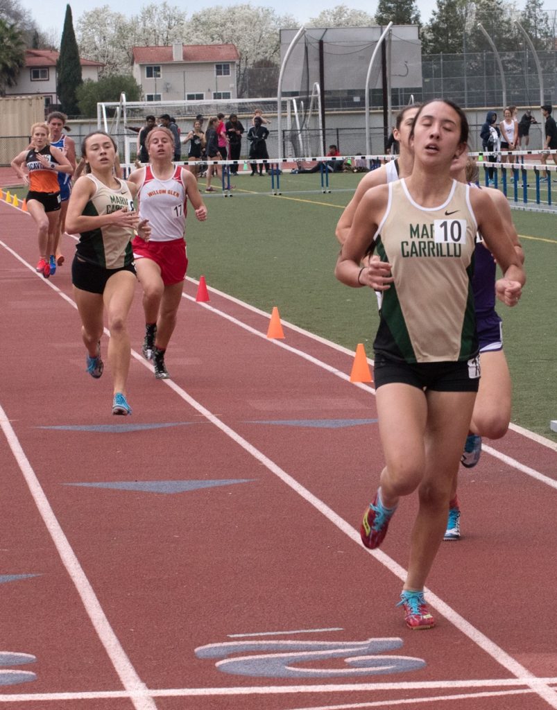 Athlete prepares for pole vault on a track with others watching.