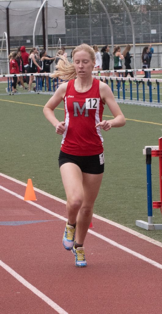 Athlete prepares for pole vault on a track with others watching.
