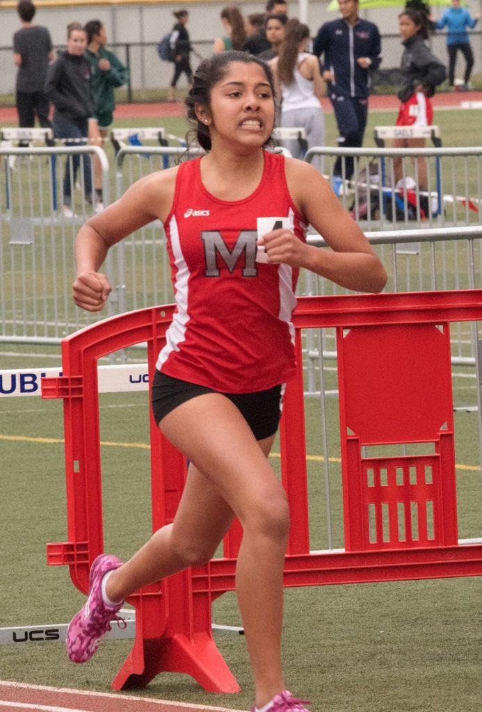 Athlete prepares for pole vault on a track with others watching.