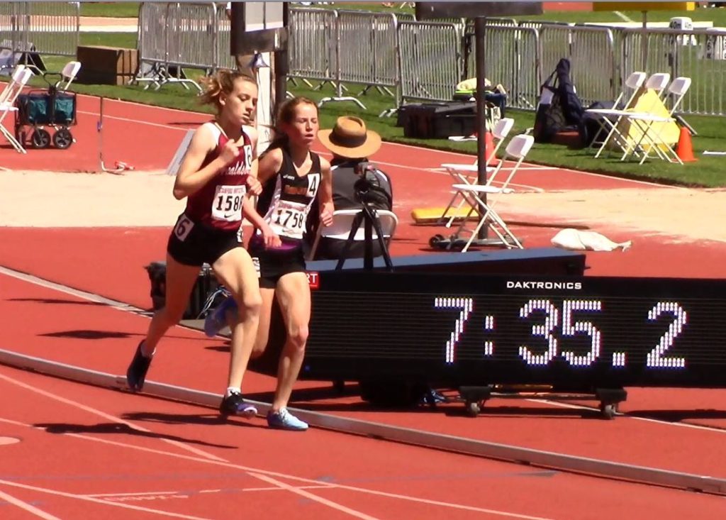 Athlete prepares for pole vault on a track with others watching.