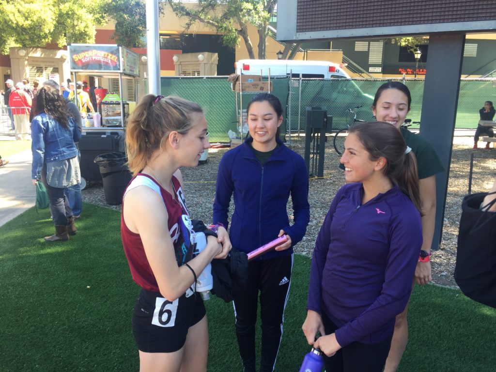 Athlete prepares for pole vault on a track with others watching.
