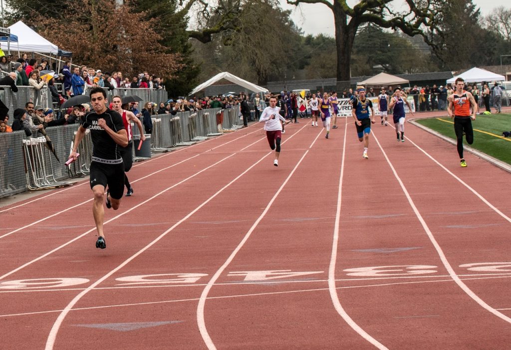 Athlete prepares for pole vault on a track with others watching.