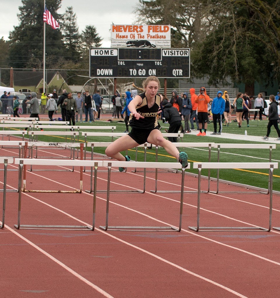 Athlete prepares for pole vault on a track with others watching.