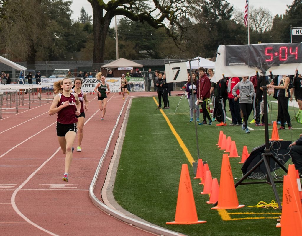 Athlete prepares for pole vault on a track with others watching.