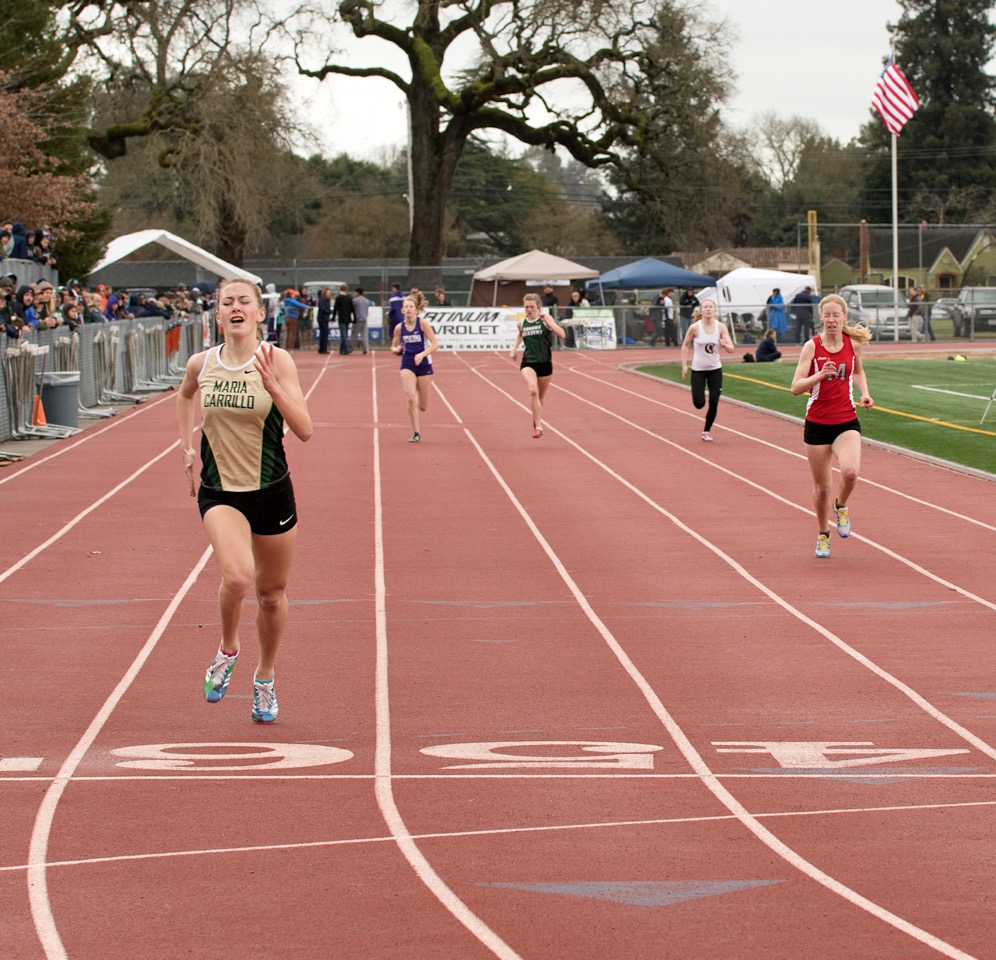 Athlete prepares for pole vault on a track with others watching.
