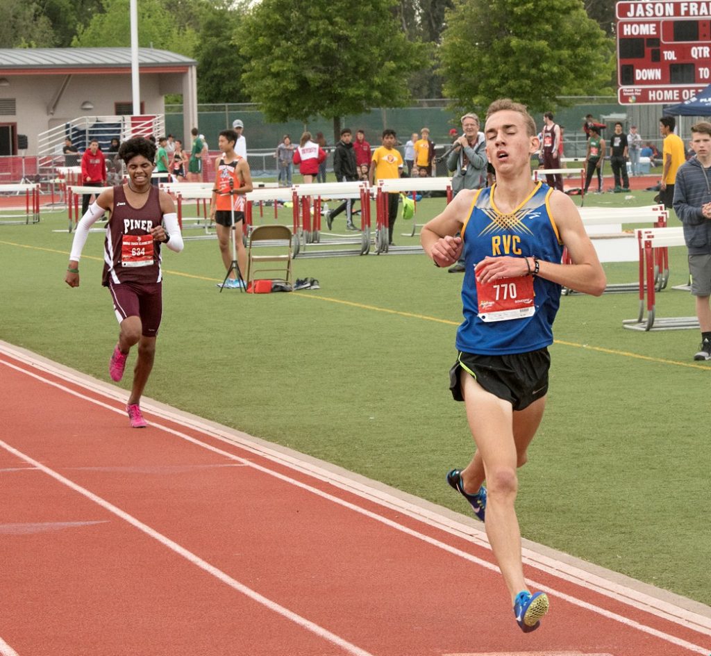 Athlete prepares for pole vault on a track with others watching.