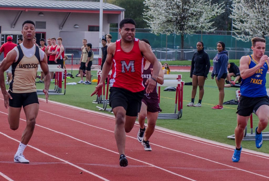 Athlete prepares for pole vault on a track with others watching.